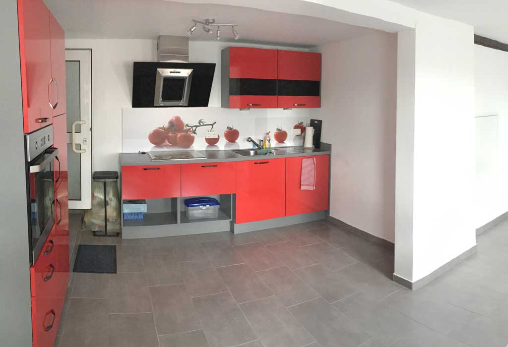 Küchenzeile mit roter Front und grau gefliestem Boden