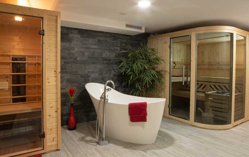 Infrarotkabine, freistehende weiße Badewanne und Sauna im Wellnessbereich in Streudorf