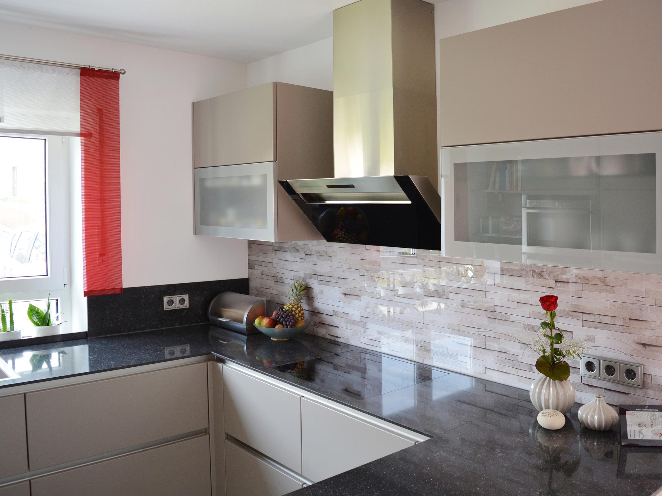 Moderne Küche mit schwarz polierter Arbeitsplatte und hellgrauer Küchenfront