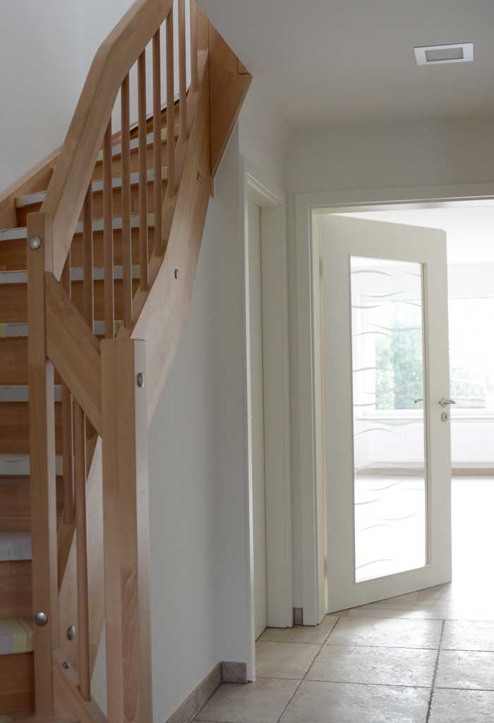 Neue Holztreppe und weißer Wohnzimmertür mit Glaselement