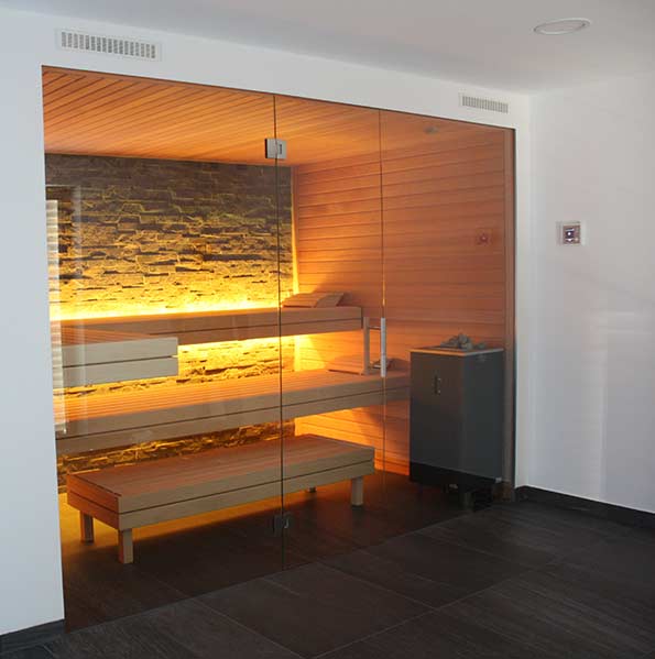Moderne Sauna mit Steinwand und Glasfront