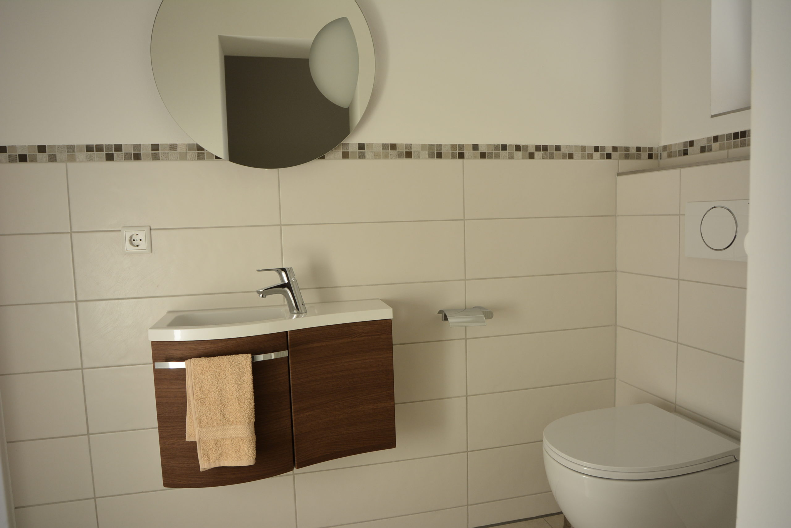 Gäste WC mit Handwaschbecken und rundem Wandspiegel