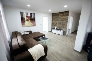 Wohnzimmer mit braunem Lounge-Sofa und Wohnwand aus Stein